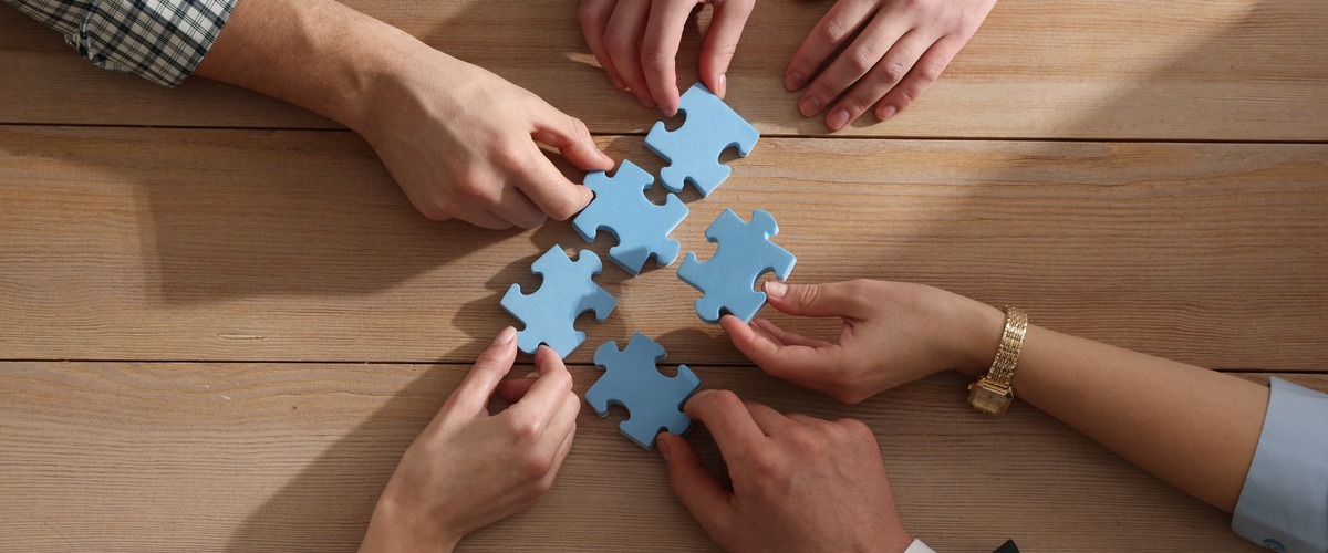 Hände halten einzelne Puzzleteile, die zusammenpassen